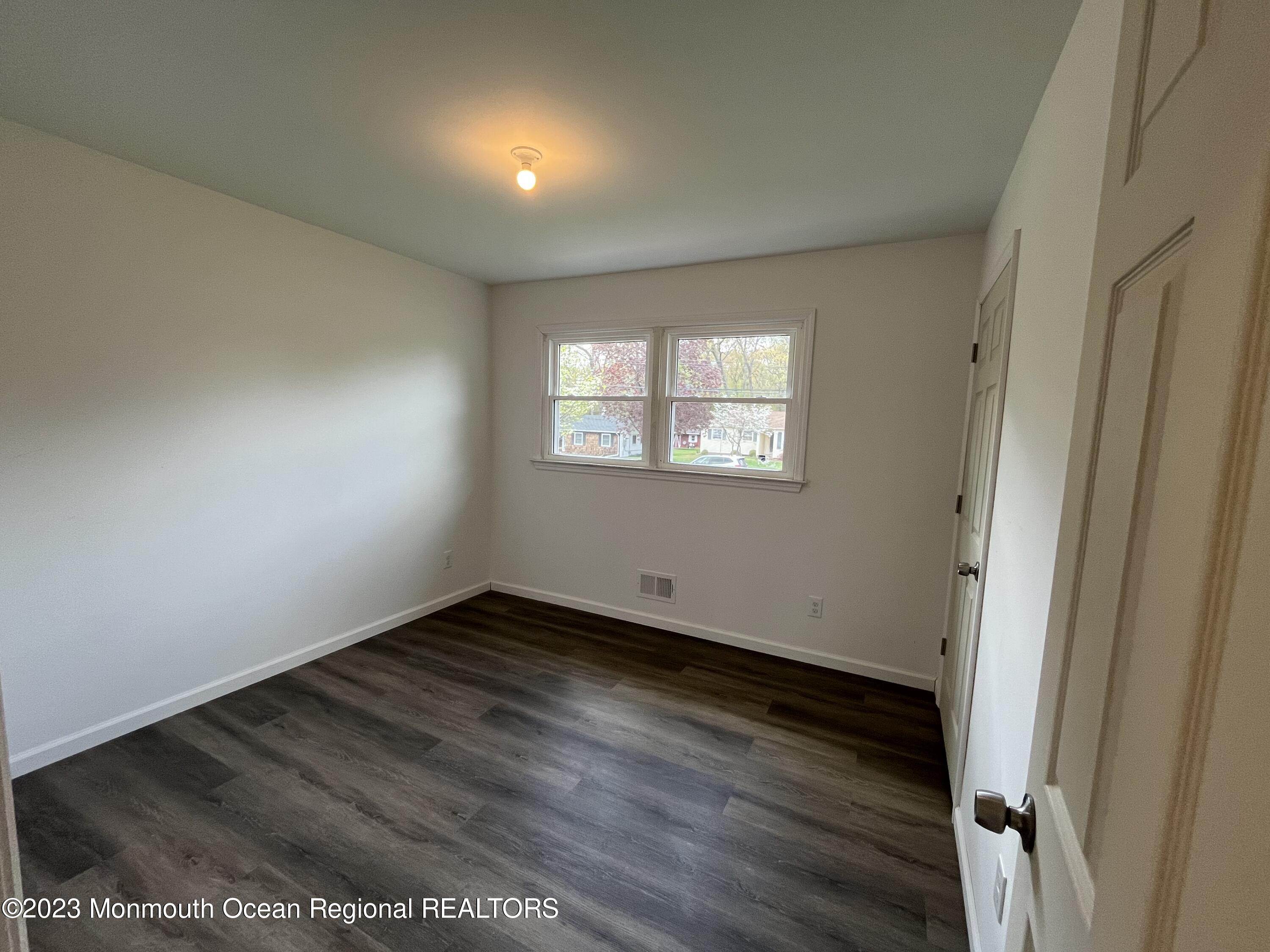 21 Glenmore Road Freehold, NJ 07728 - Photo 11 of 14 an empty room with wooden floor and windows