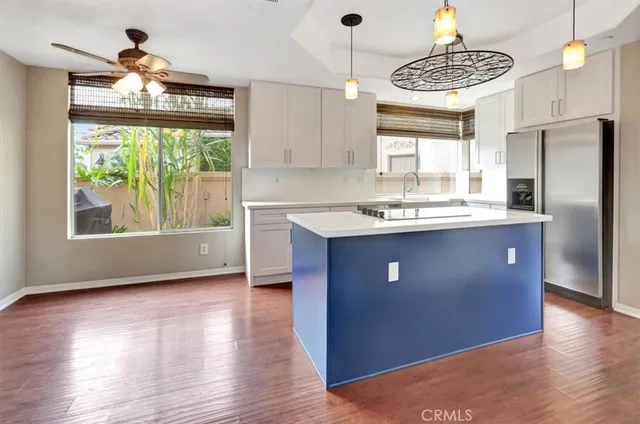 a kitchen with stainless steel appliances granite countertop a sink a stove a refrigerator cabinets and wooden floor