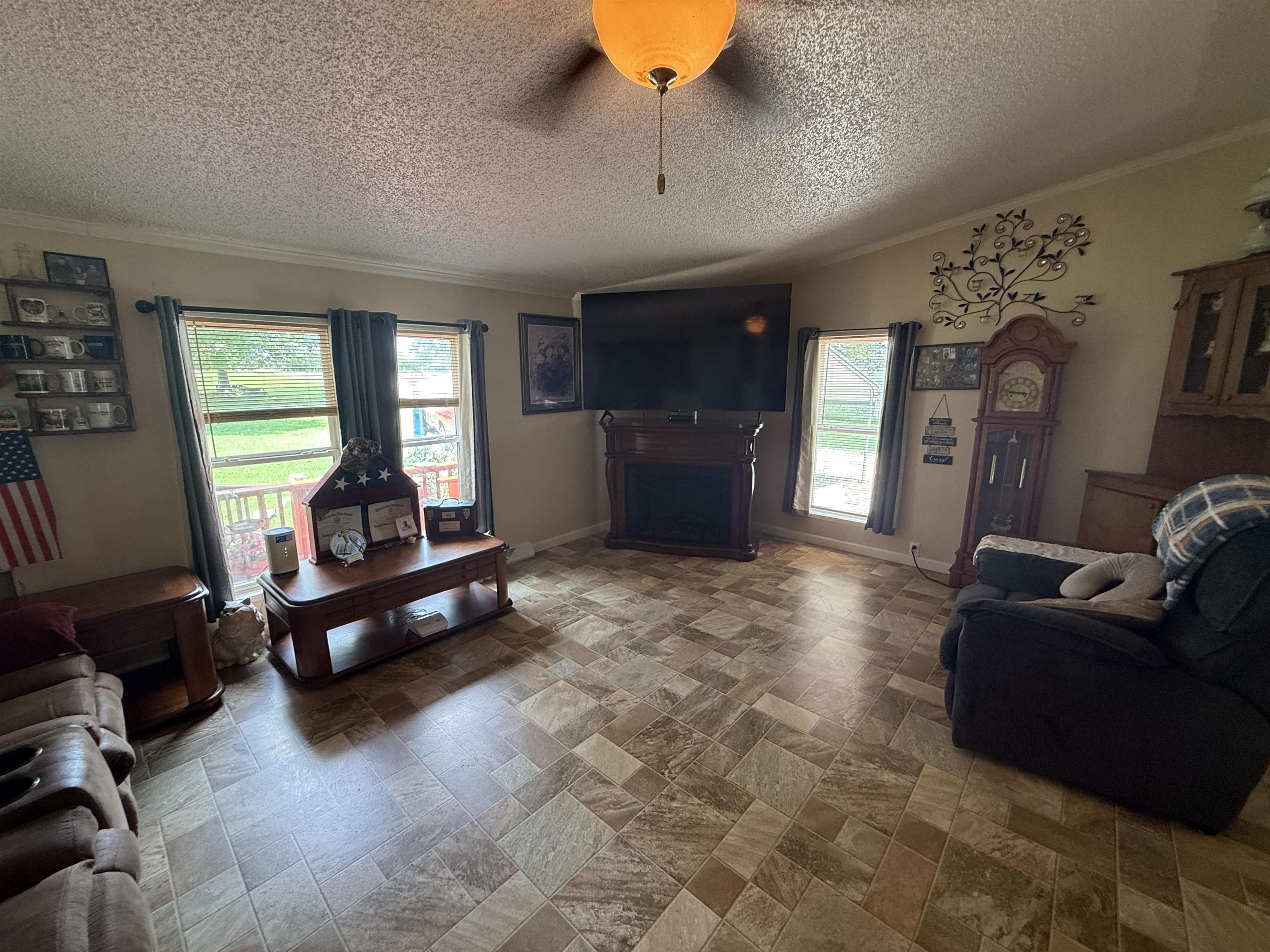 2201 Robert Johnson Road Covington, TN 38019 - Photo 14 of 25 Spacious living area featuring patterned tile flooring, a built-in electric fireplace with mantel, crown molding, and two large windows offering outdoor visibility