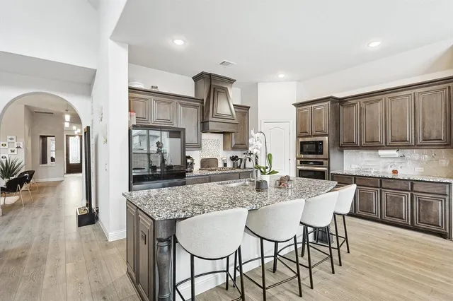 a kitchen with stainless steel appliances granite countertop a stove top oven a sink dishwasher and cabinets with wooden floor