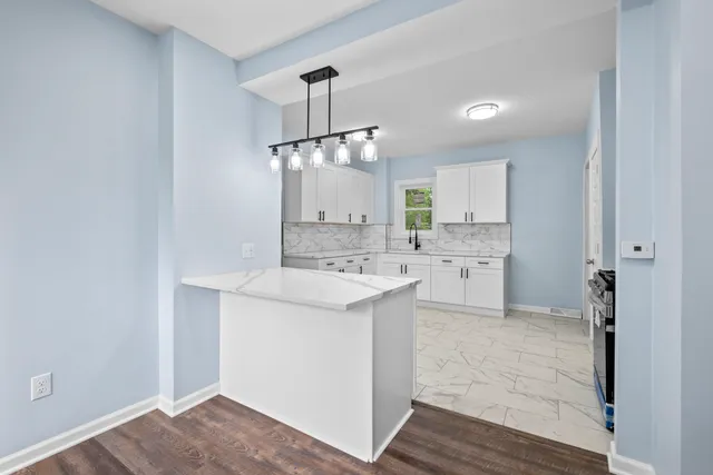 a kitchen that has a lot of white cabinets and stainless steel appliances