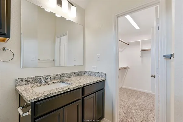 a bathroom with a granite countertop sink and a mirror
