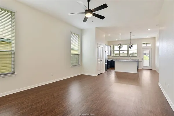 a view of a hallway with wooden floor and a kitchen
