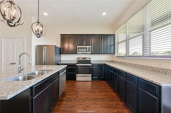 a kitchen with stainless steel appliances granite countertop a sink a stove top oven and wooden floors