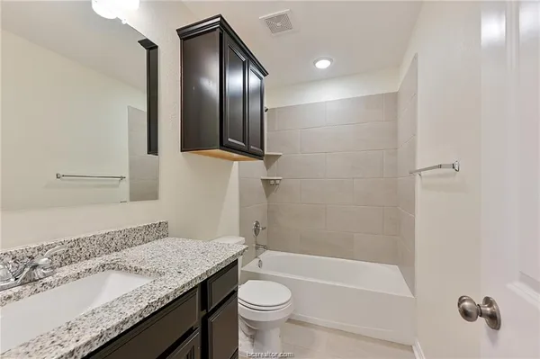 a bathroom with a granite countertop sink toilet and shower