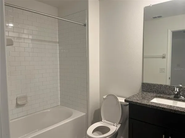 a bathroom with a granite countertop sink toilet and shower