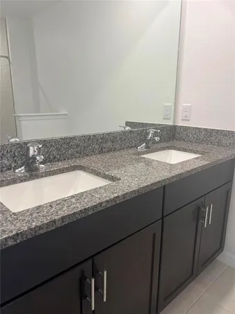 a bathroom with a granite countertop sink and a large mirror
