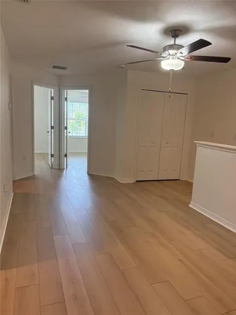 a view of a room with wooden floor and ceiling fan