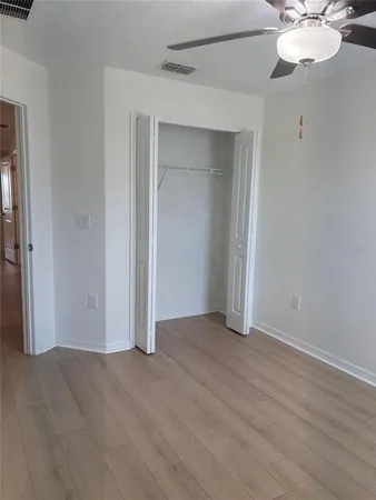 an empty room with wooden floor and fan