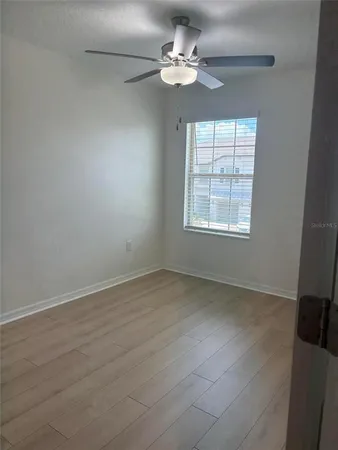 an empty room with chandelier fan and windows