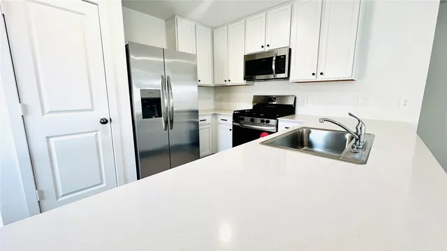 a kitchen with refrigerator a microwave a sink and cabinets