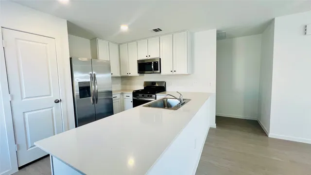 a kitchen with a refrigerator a stove and white cabinets