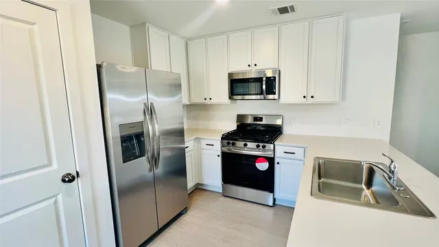 a kitchen with stainless steel appliances granite countertop a refrigerator a stove and a sink