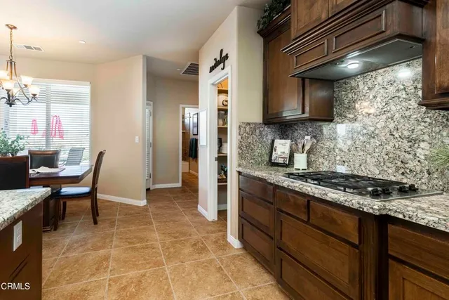 a kitchen with stainless steel appliances granite countertop a refrigerator a sink a stove a dining table and chairs