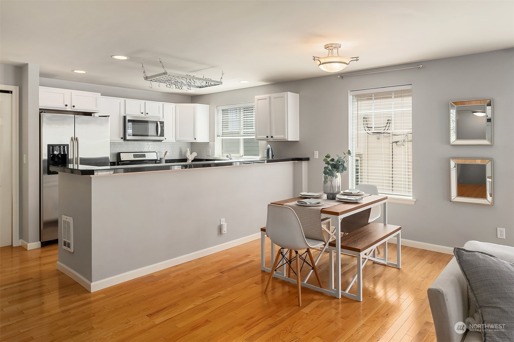 8517 Interlake Avenue North, Unit A Seattle, WA 98103 - Photo 6 of 20 a kitchen with stainless steel appliances granite countertop a stove top oven a sink dishwasher and a dining table with wooden floor