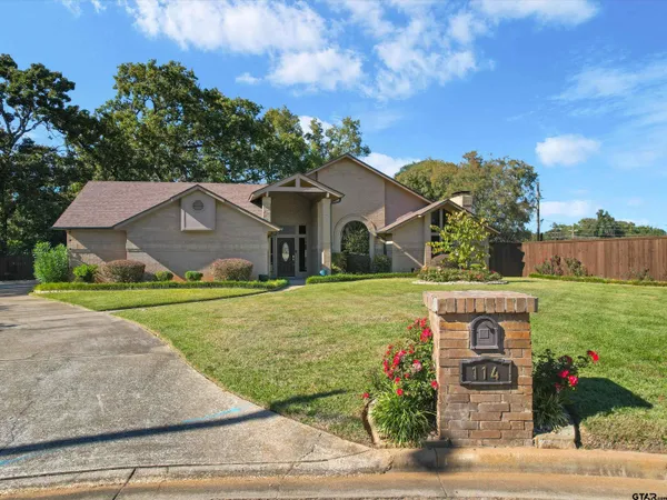 a front view of house with yard and trees in the background