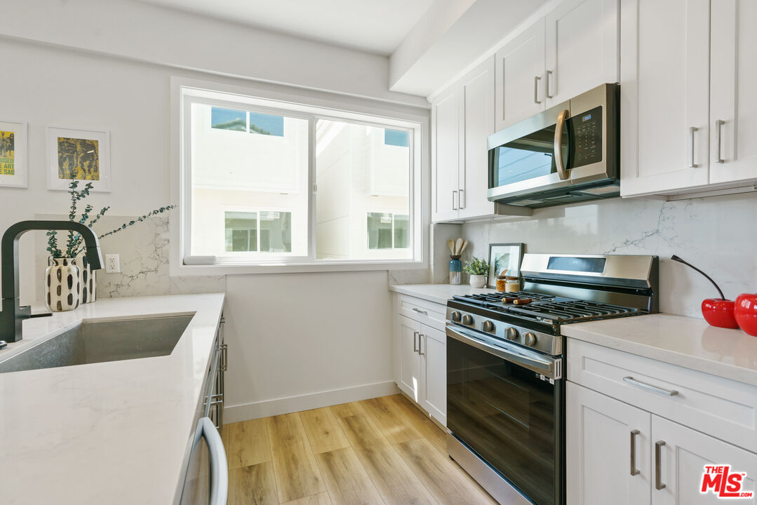 14652 West Sara Lane Panorama City, CA 91402 - Photo 14 of 33 a kitchen with stainless steel appliances a stove a sink a microwave cabinets and a window