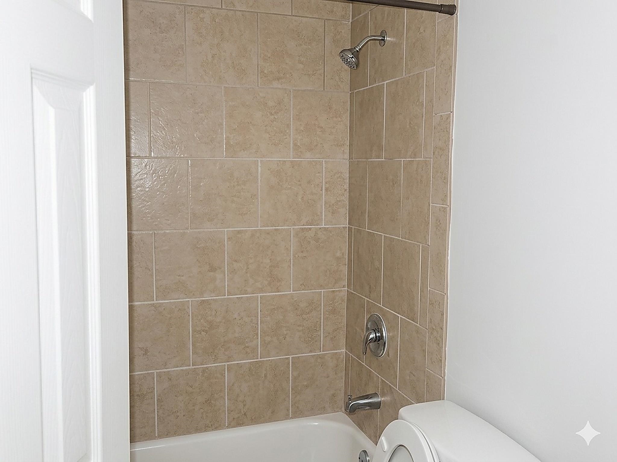 4444-4446 Sumners Wells Road Memphis, TN 38118 - Photo 7 of 8 Bathtub with light-colored tile surround, chrome shower head, and chrome faucet