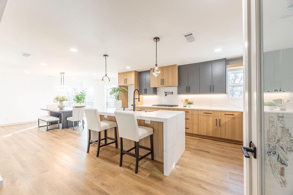 8713 Clay Hibbins Road Keller, TX 76248 - Photo 31 of 40 a kitchen with kitchen island granite countertop wooden floors and white cabinets