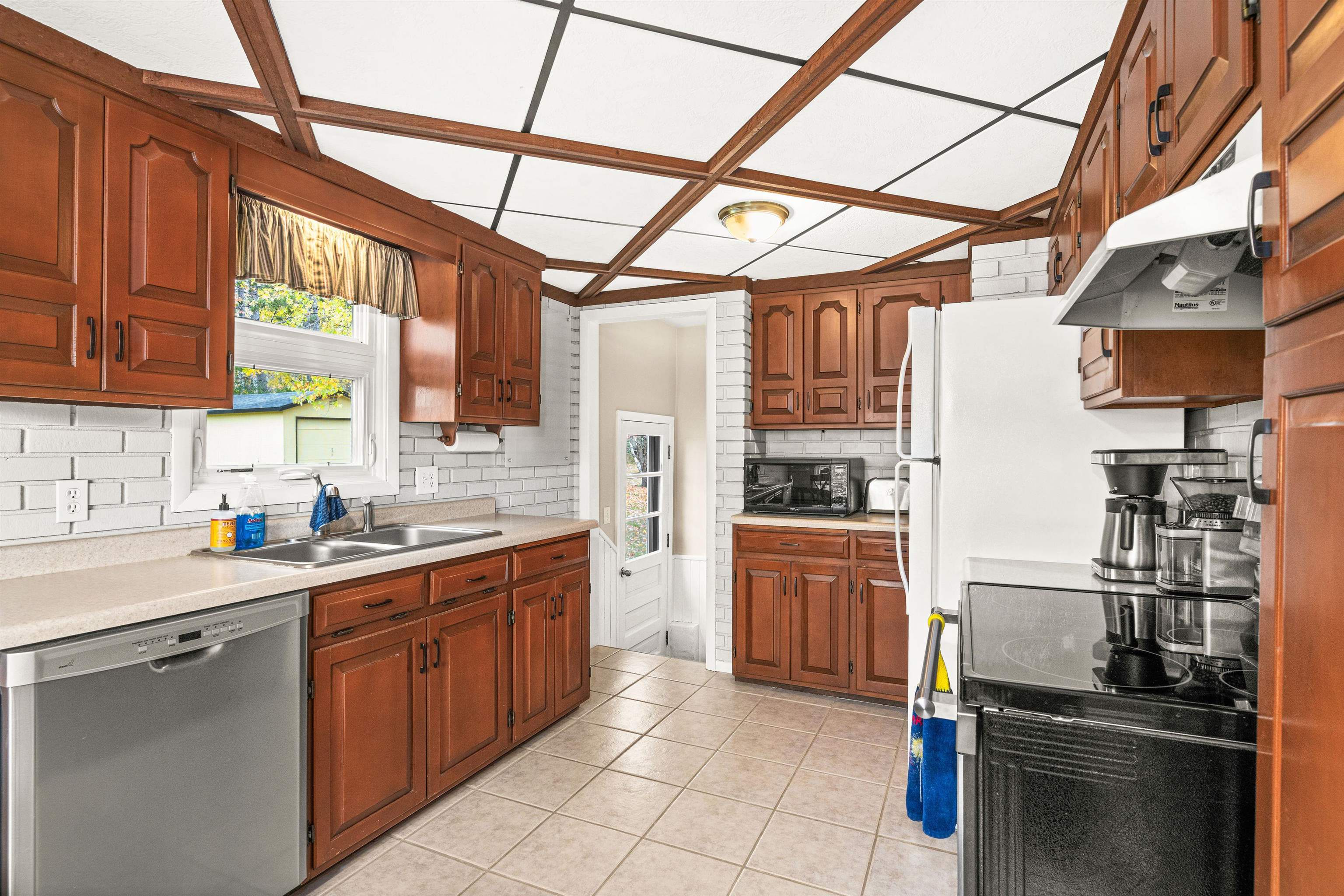 4319 Decker Road Duluth, MN 55811 - Photo 7 of 28 Kitchen featuring decorative backsplash, dishwasher, light tile patterned floors, light countertops, and under cabinet range hood