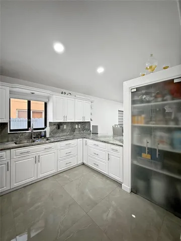 a kitchen with granite countertop white cabinets and white appliances