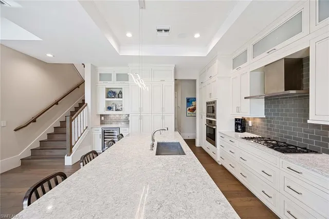 a large white kitchen with granite countertop lots of counter space wooden floor and stainless steel appliances