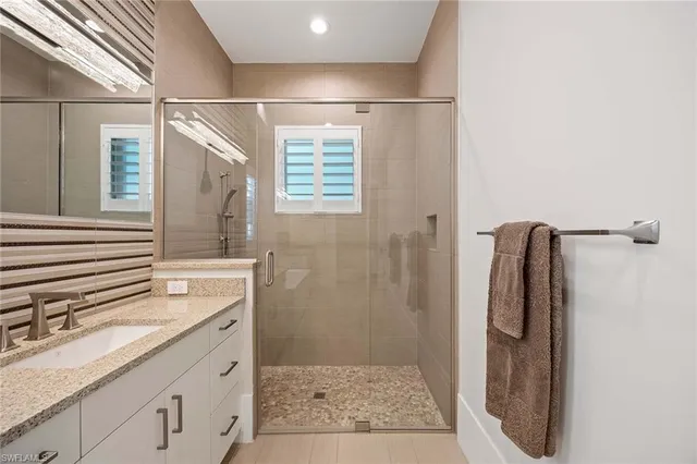 a bathroom with a granite countertop shower sink and mirror