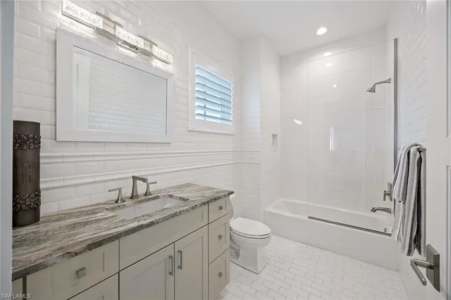 a bathroom with a granite countertop sink a toilet and shower