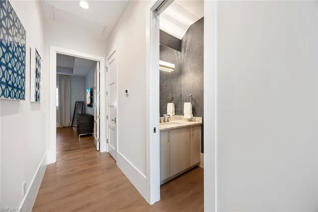 a view of a hallway with wooden floor and a bathroom
