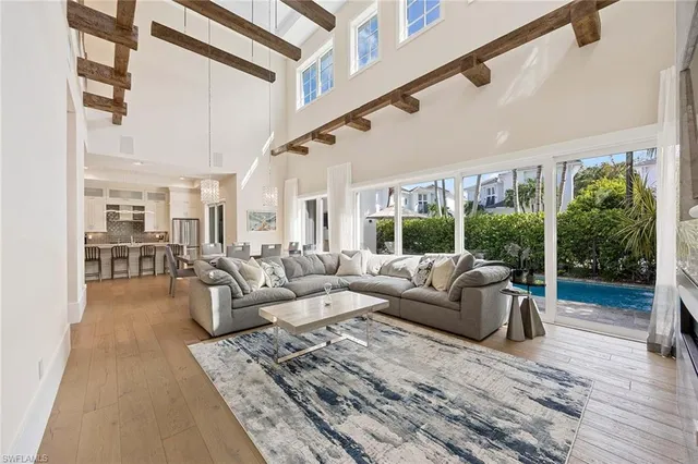 a living room with furniture large windows and wooden floor
