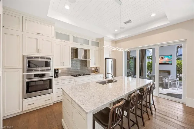 a kitchen with stainless steel appliances granite countertop a stove top oven a refrigerator a sink and a dining table with wooden floor