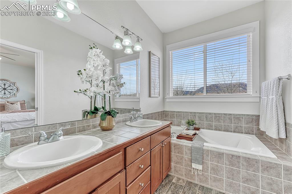 16946 Buffalo Valley Path Monument, CO 80132 - Photo 20 of 41 a bathroom with a granite countertop sink a large mirror and a bathtub with shower