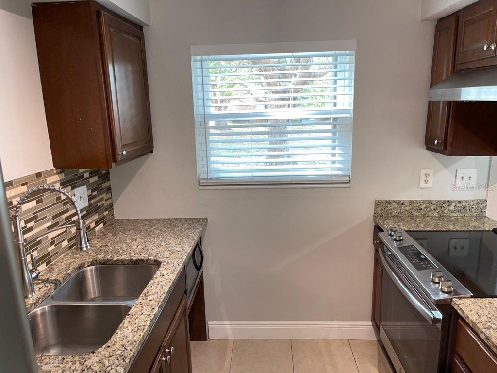 5325 Curry Ford Road, Unit B101 Orlando, FL 32812 - Photo 7 of 22 a kitchen with granite countertop a sink and a stove top oven