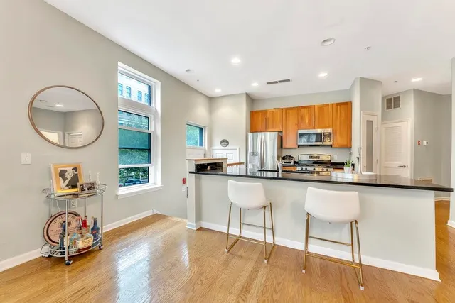 a kitchen with stainless steel appliances granite countertop a stove top oven a sink a dining table and chairs with wooden floor