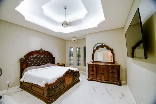 a spacious bedroom with a bed a fireplace and a chandelier