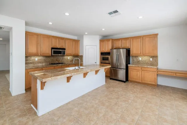 a large kitchen with stainless steel appliances granite countertop a lot of counter space and a sink