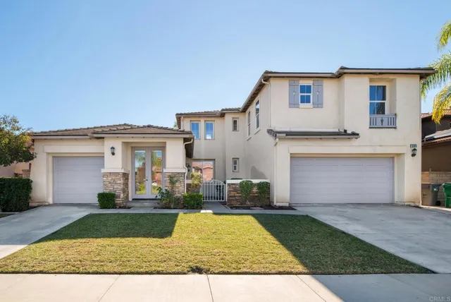 a view of a white house with a small yard and a large tree