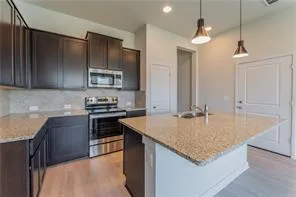 a kitchen with kitchen island granite countertop a sink a counter top space appliances and cabinets