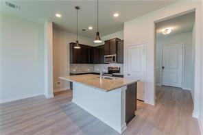 15107 Ryman Road Pflugerville, TX 78660 - Photo 5 of 34 a kitchen with stainless steel appliances granite countertop a sink a stove and a wooden floors