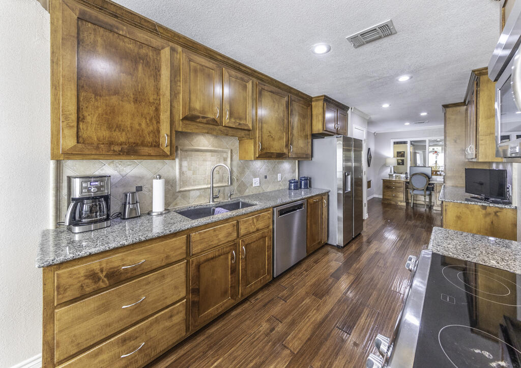3620 93rd Street Lubbock, TX 79423 - Photo 13 of 33 a kitchen with stainless steel appliances granite countertop wooden floors a stove and a sink