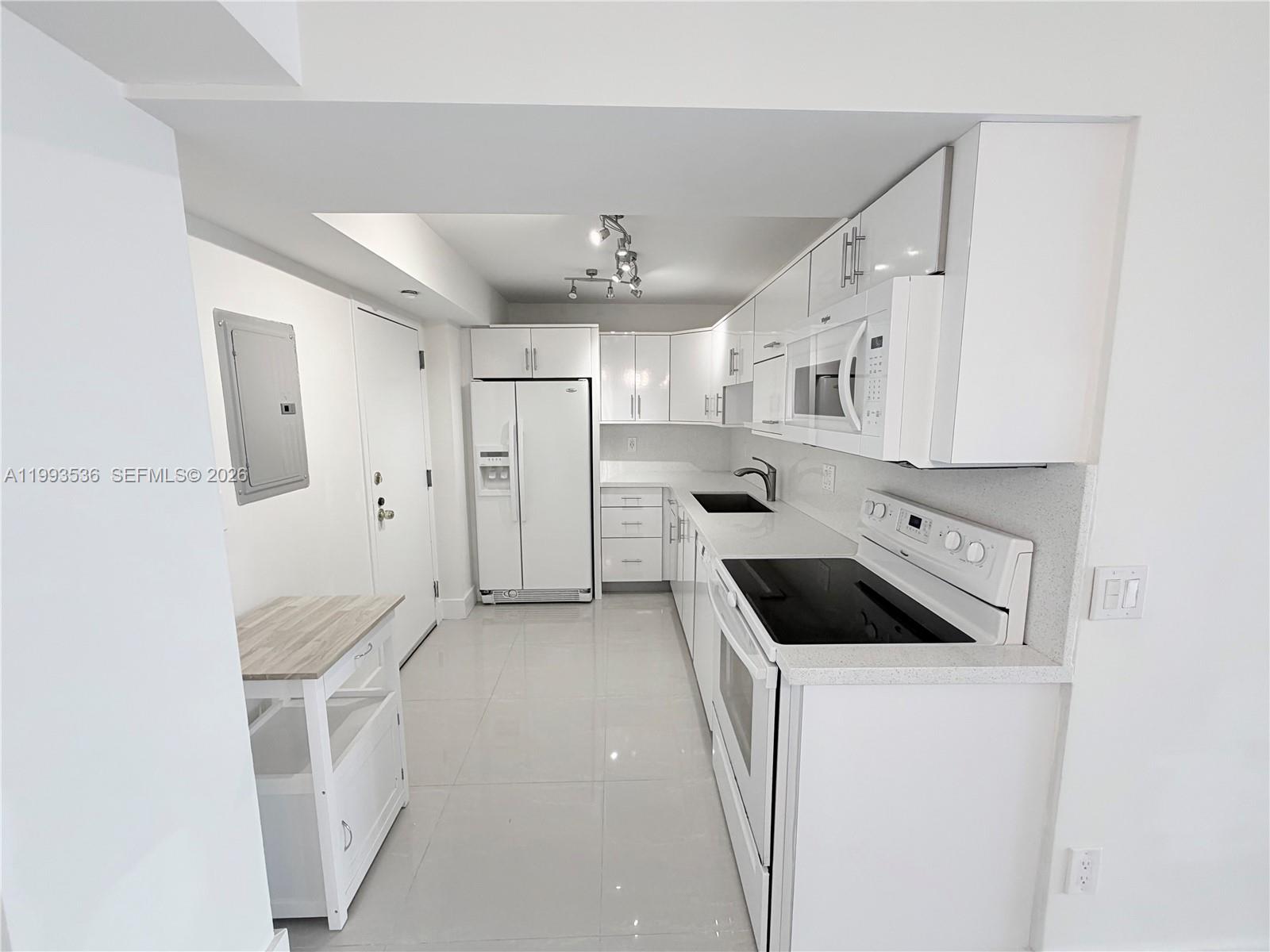2333 Brickell Avenue, Unit 1407 Miami, FL 33129 - Photo 3 of 38 a kitchen with white cabinets and white appliances