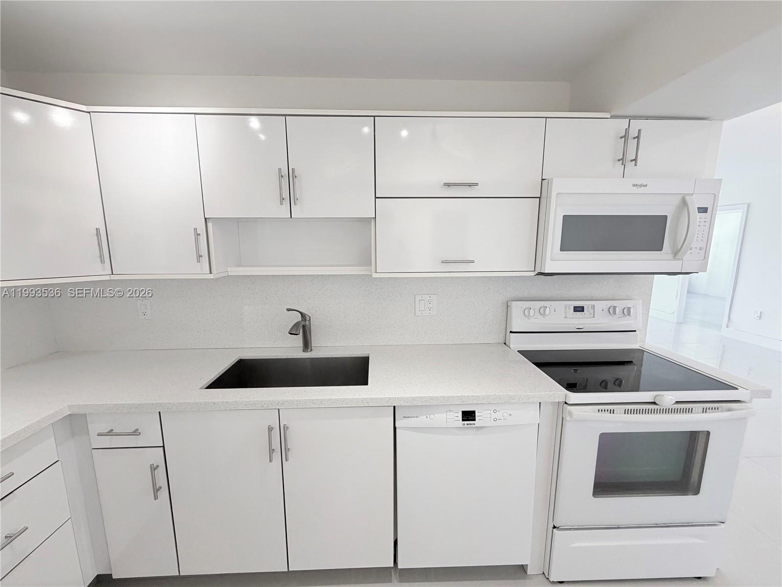 2333 Brickell Avenue, Unit 1407 Miami, FL 33129 - Photo 4 of 38 a kitchen with white cabinets and white appliances