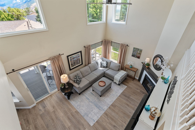 14883 Tooele Lane Draper, UT 84020 - Photo 23 of 49 Vaulted living area featuring wood-finish flooring, a fireplace with a dark surround and white mantle, and a sliding glass door opening to an outdoor deck