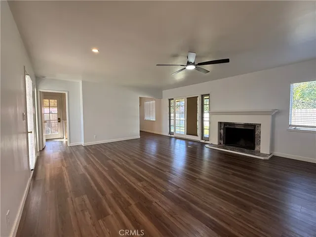 an empty room with wooden floor fireplace and windows