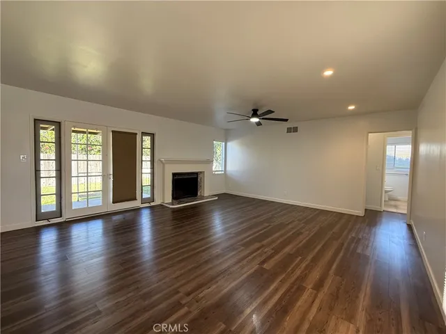 an empty room with wooden floor fireplace and windows