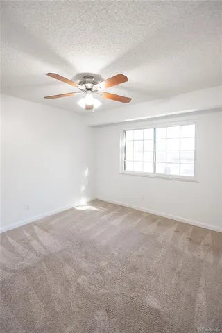 an empty room with windows and chandelier fan