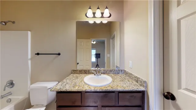 a bathroom with a granite countertop sink a mirror and a bathtub