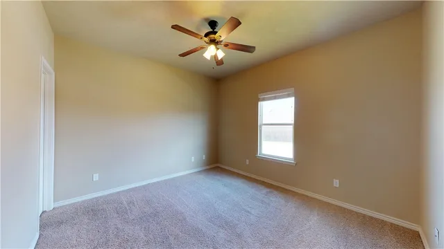 an empty room with windows and ceiling fan