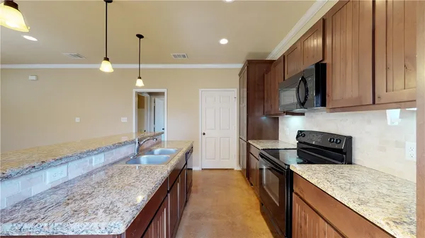 a kitchen with stainless steel appliances granite countertop a sink a stove and a wooden cabinets