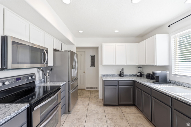 5485 Heather Way Tooele, UT 84074 - Photo 22 of 41 Kitchen featuring a two-tone cabinetry design, stainless steel appliances, granite countertops, recessed lighting, and tile flooring